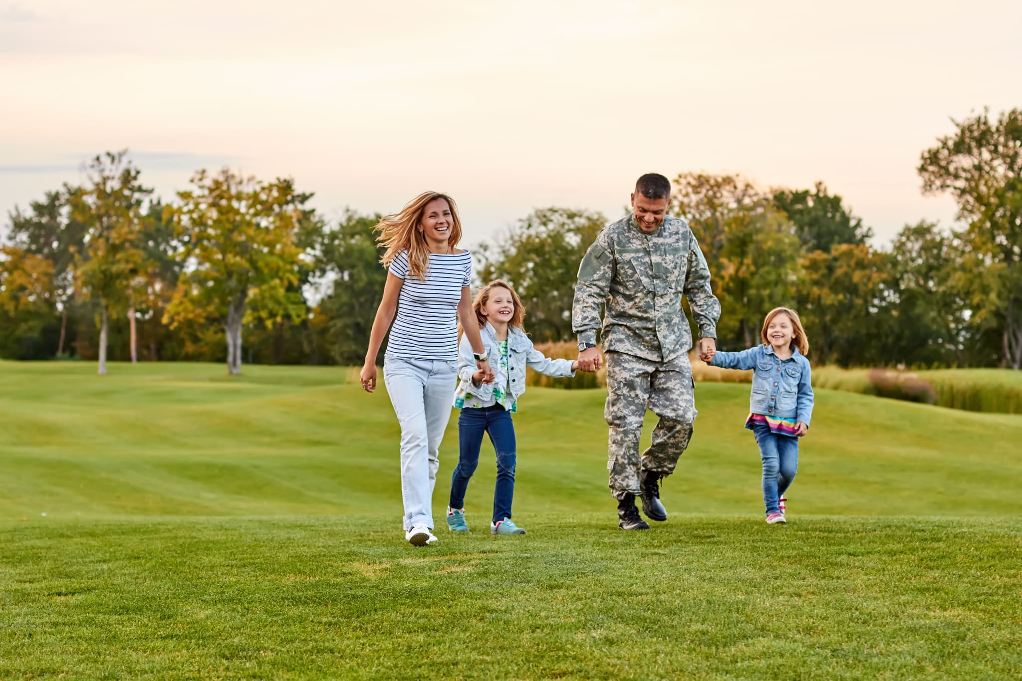 Veteran walking with family on grass field.